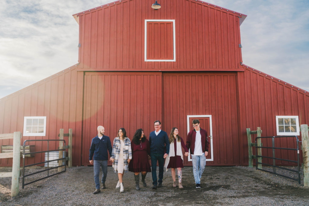winter session location with family of six posing in front of red barn