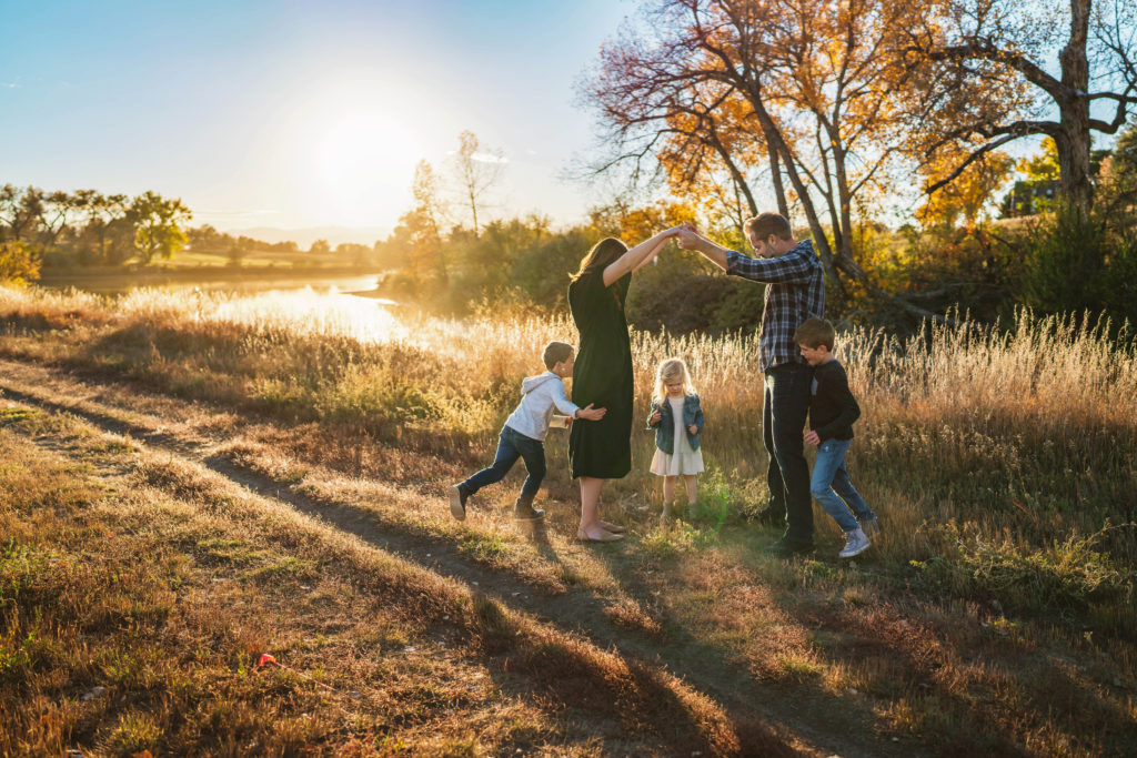 family plays london bridge during family photo session in colorado