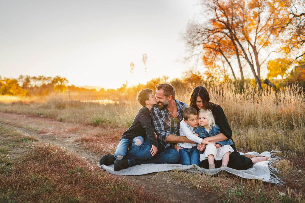 family snuggled up on blanket with beautiful fall colors in denver meadow