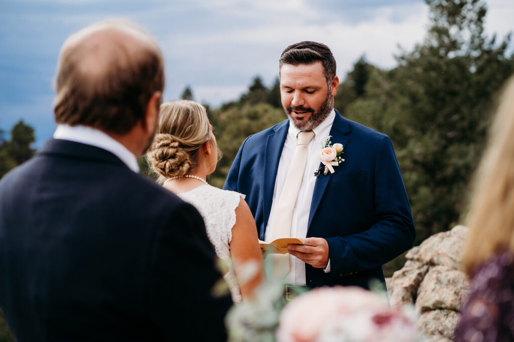 Colorado Elopement Photographer captures groom reading vows during intimate wedding ceremony