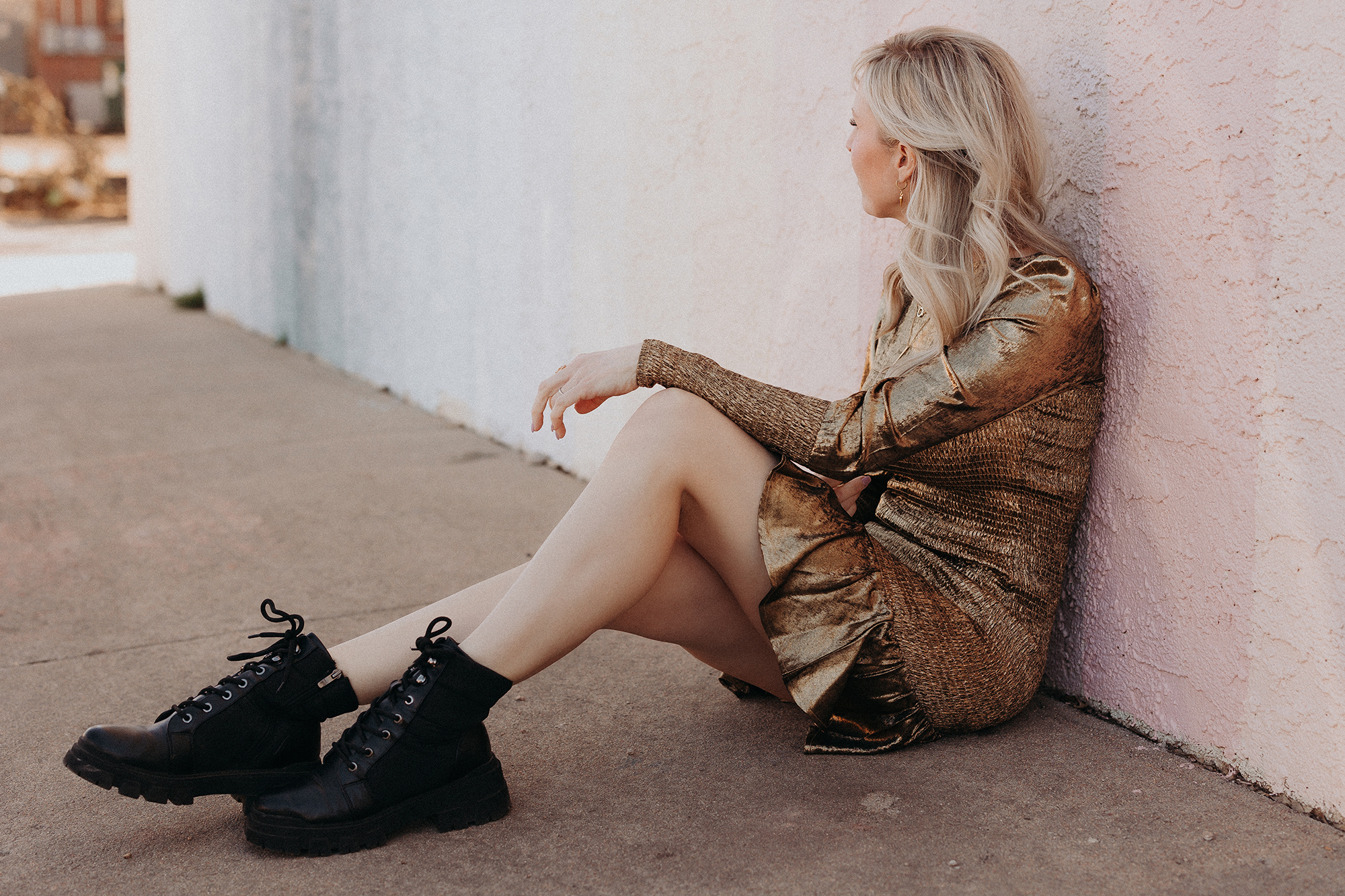 woman sitting on ground in denver wearing short gold dress and black boots