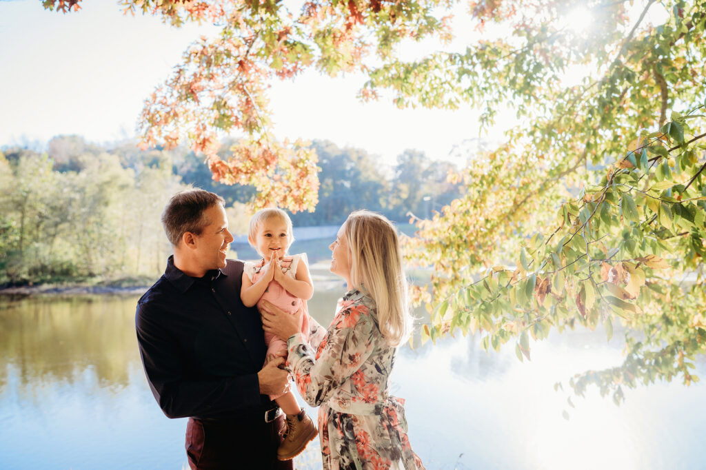 Virginia waterfront provides a lovely backdrop to a family standing under a tree in photo by Denver family photographers