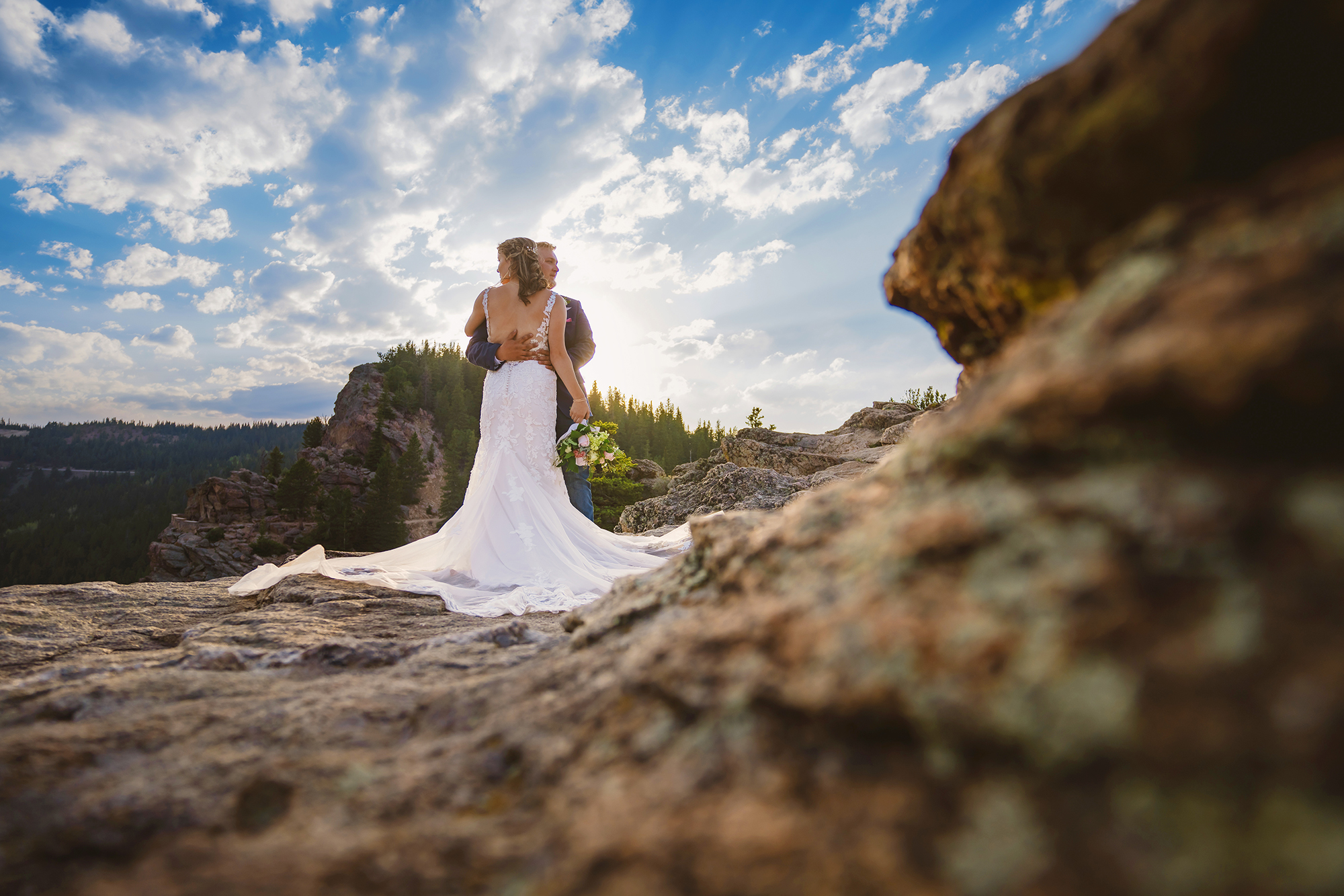Colorado elopement photographer captures a bride in a low-back dress embracing her groom on a mountain top