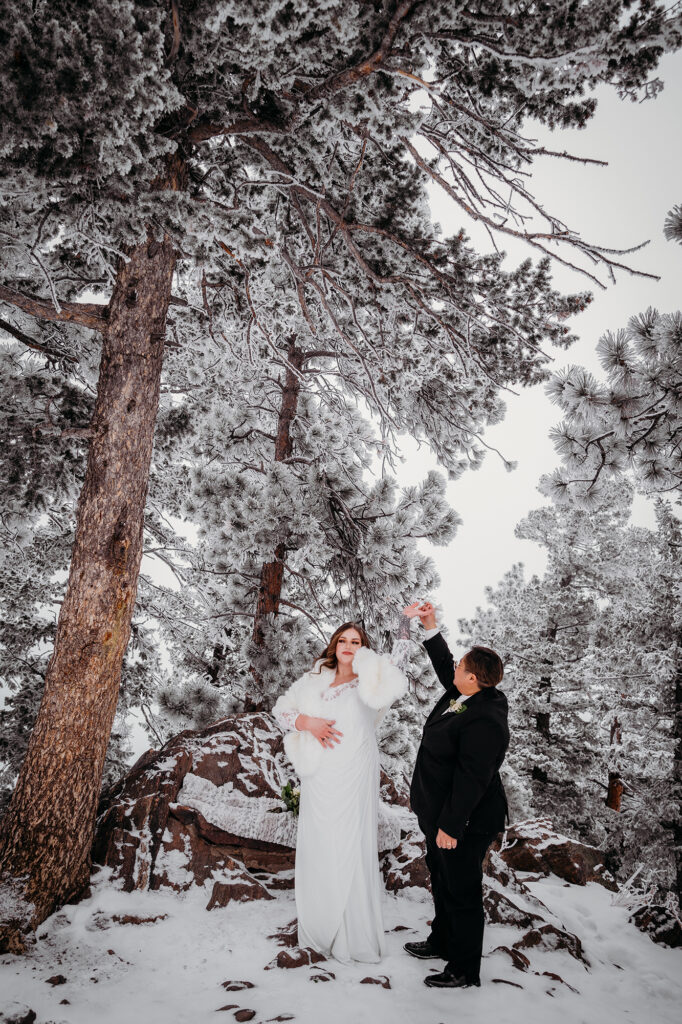 Colorado elopement photographer captures A bride twirls her partner in the snow in a winter wedding photo by a Colorado elopement photographer