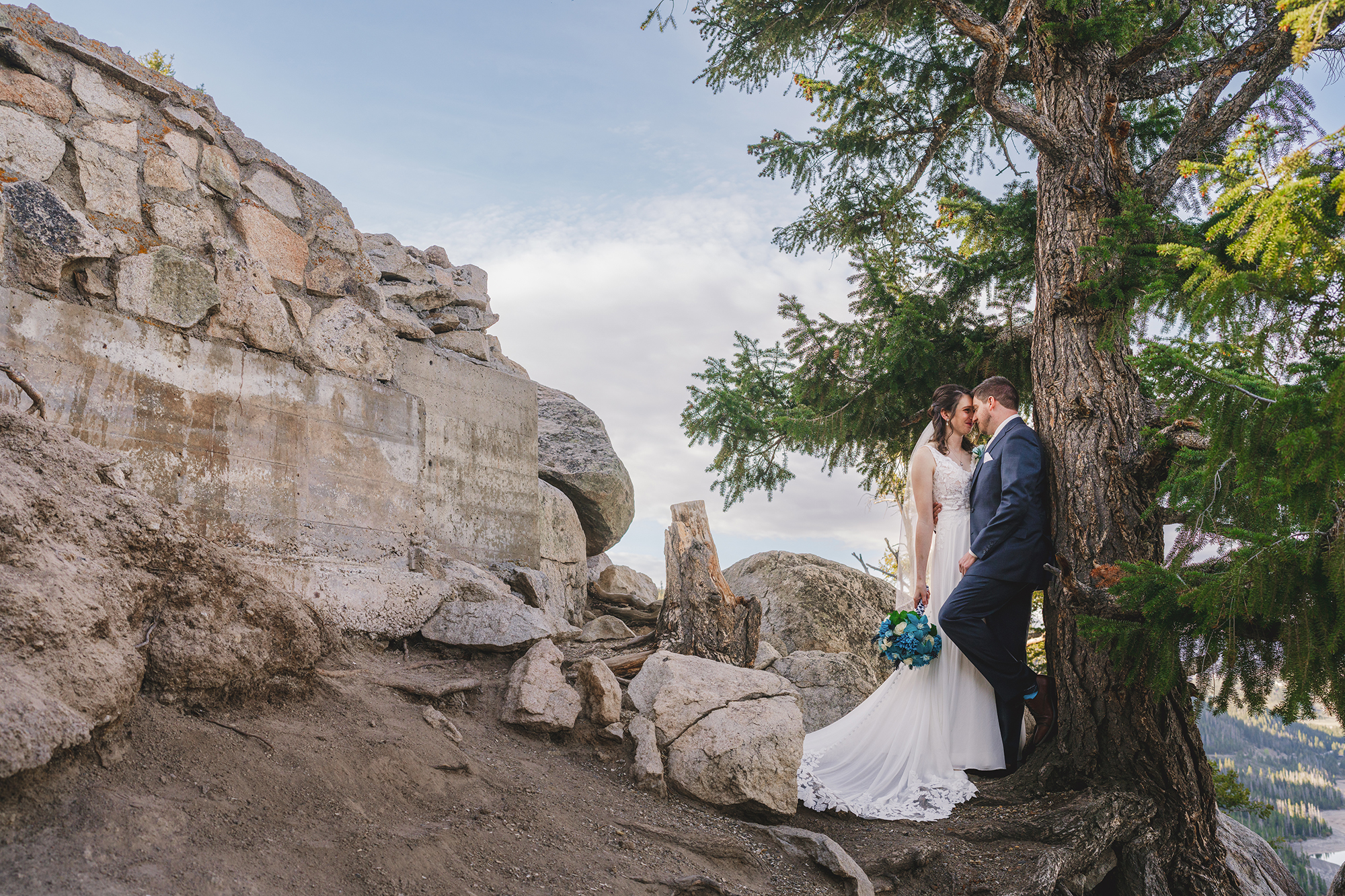 Colorado elopement Photographer captures bride and groom on the top of a mountain with ridged cliff edges behind them as they embrace one another for outdoor wedding pictures