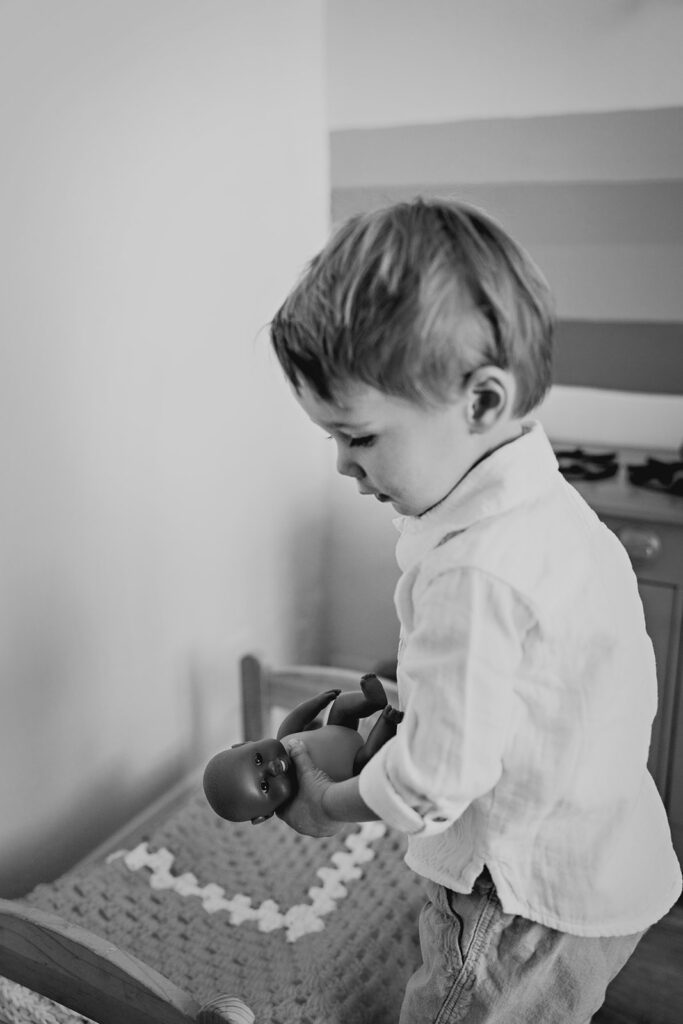 black and white candid picture of little boy playing with his toys during a mothers day shoot with his mom 