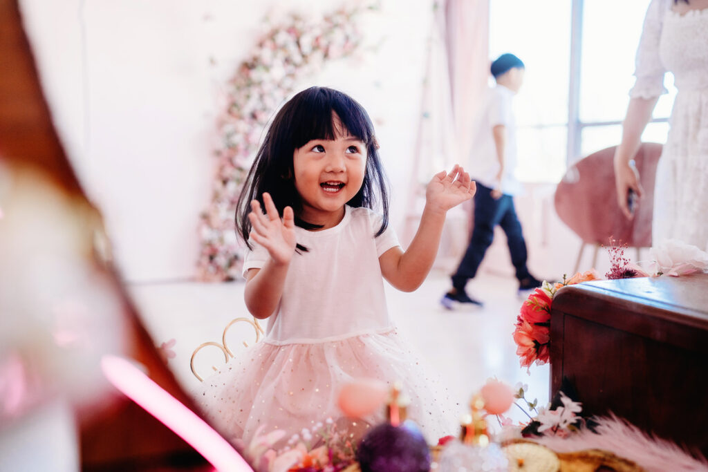 little girl in a light pink dress smiling and looking up at her mother while standing in front of a mirror captured by Denver family Photographers
