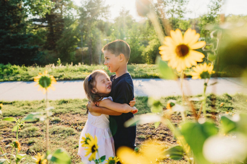 denver family photos with brother and sister hugging next to a sunflower patch captured by Denver family photographers