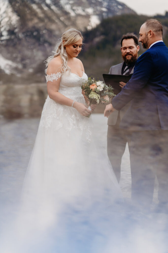 Colorado elopement photographer captures couple during wedding ceremony as bride holds bouquet. 