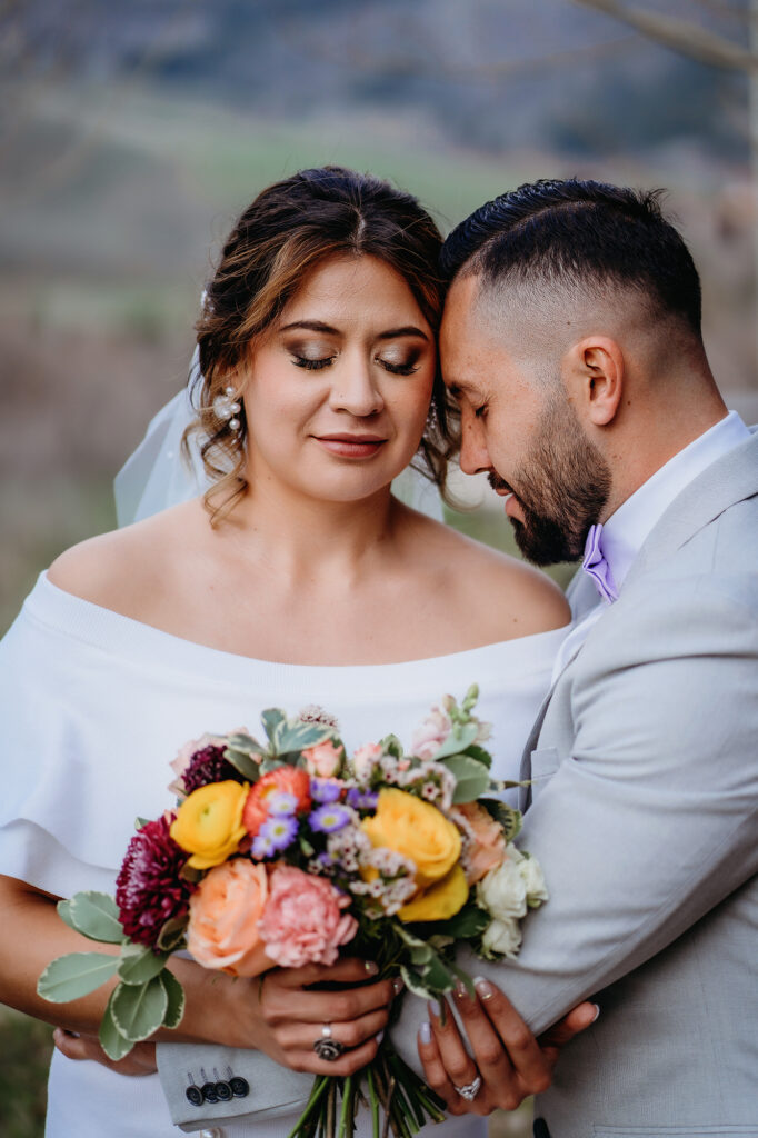 Colorado elopement photographer captures groom hugging bride while bride closes eyes and holds bouquet