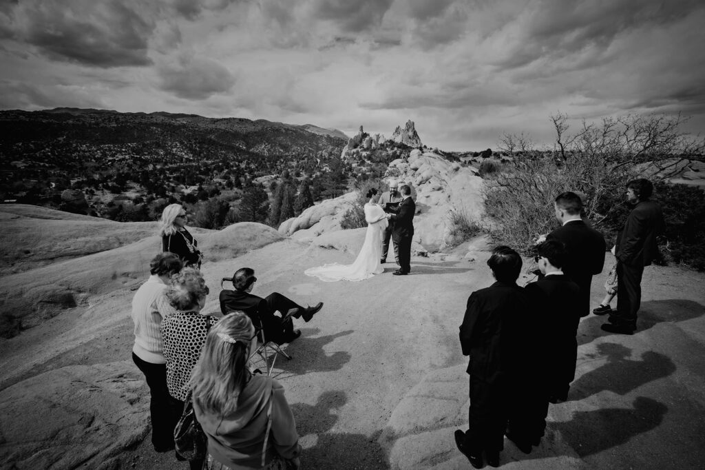 Denver wedding photographer captures ceremony on the top of a mountain in the Rockies with guests surrounding the eloping couple