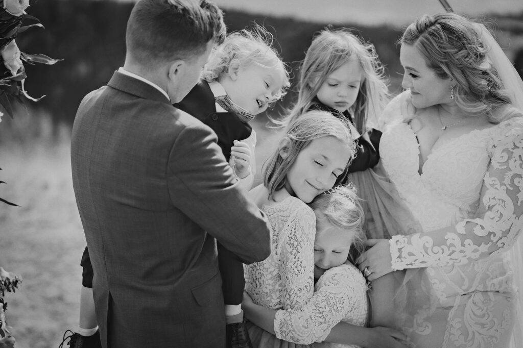 blended family picture at colorado elopement with family hugging each other under the wedding ceremony arch captured by denver wedding photographer