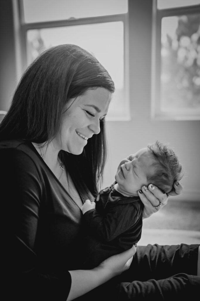 Denver family photographers capture mother holding newborn baby during in home newborn photos