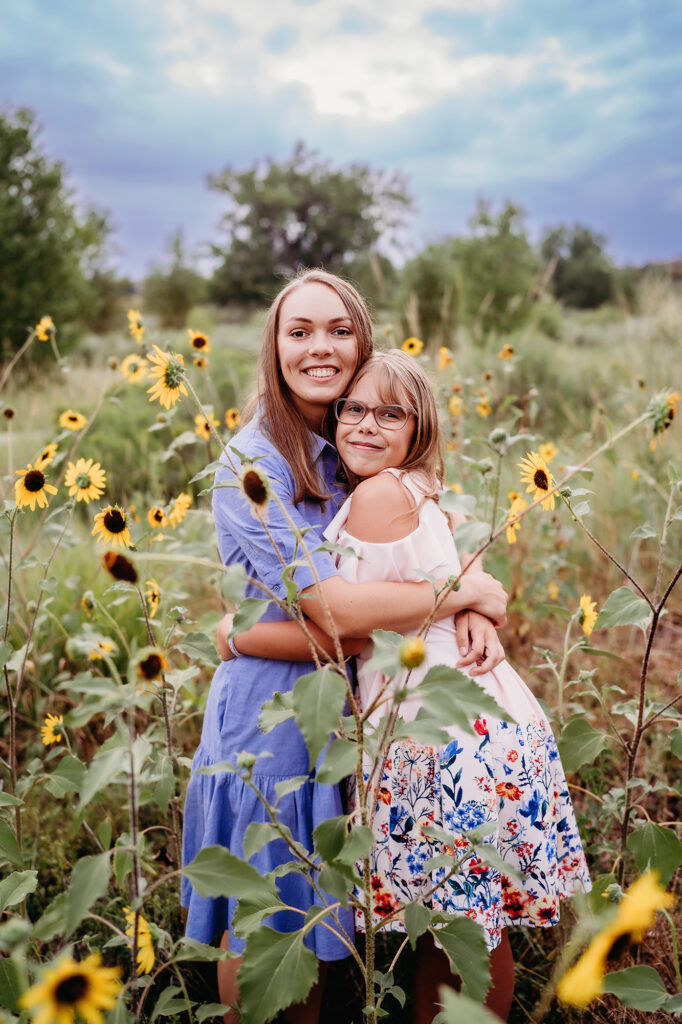 Denver Family Photographers capture sister hugging sister in sunflower photos