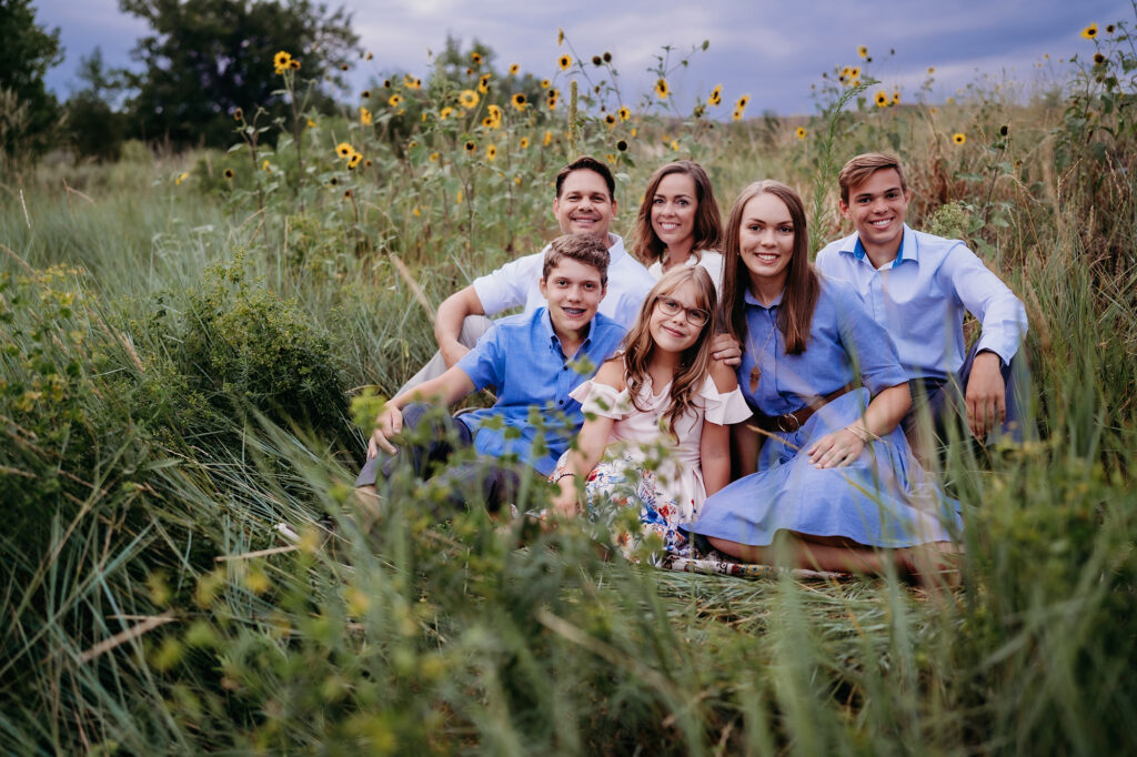 Denver family photographers capture family sitting in grass during outdoor family portraits