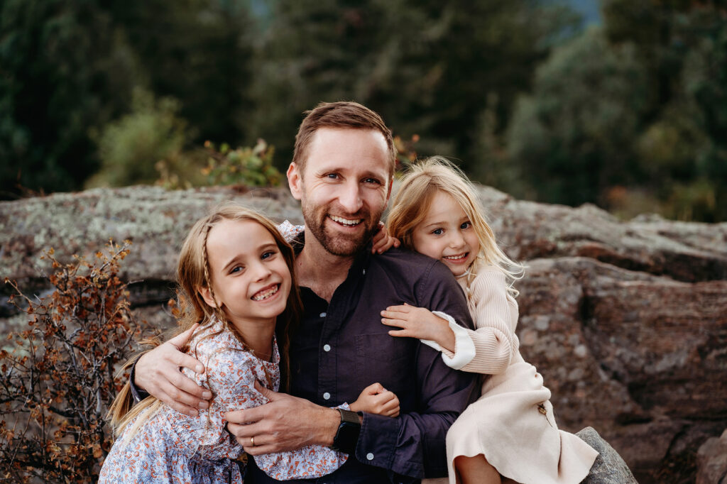 Denver Family Photographers capture father smiling during family photos with children hugging him
