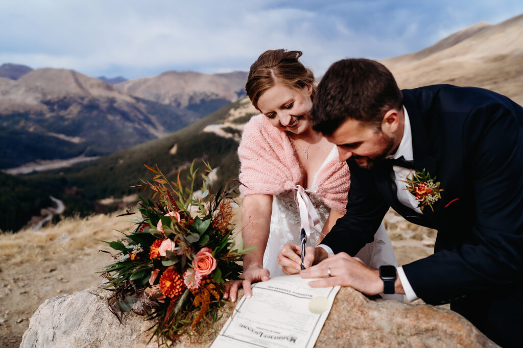 Colorado elopement photographer captures bride and groom signing marriage certificate