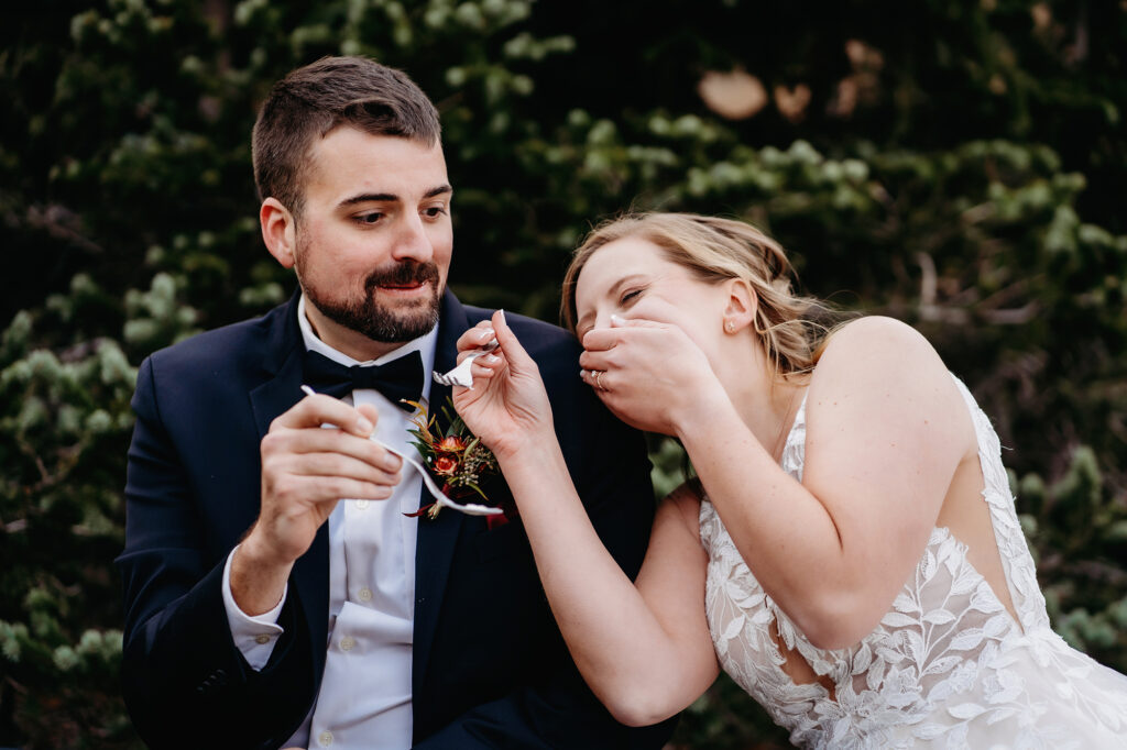 Colorado elopement photographer captures bride and groom laughing while eating cake