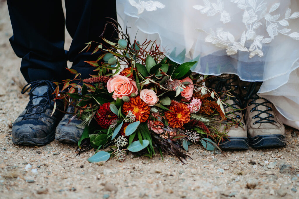 Colorado Elopement Photographer captures bride and groom wearing hiking boots with bouquet on ground after Colorado elopement experience