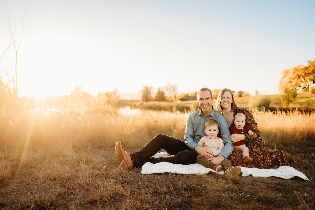 Denver Family Photographers capture family sitting on blanket during golden hour portraits