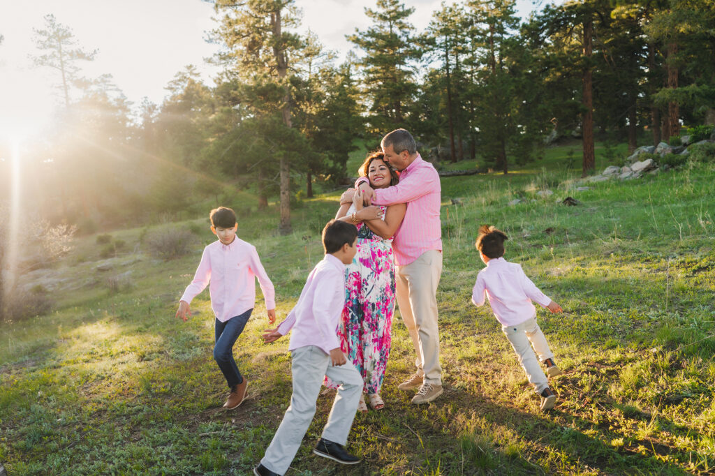 Denver Family Photographers capture mother and father kissing while children run around