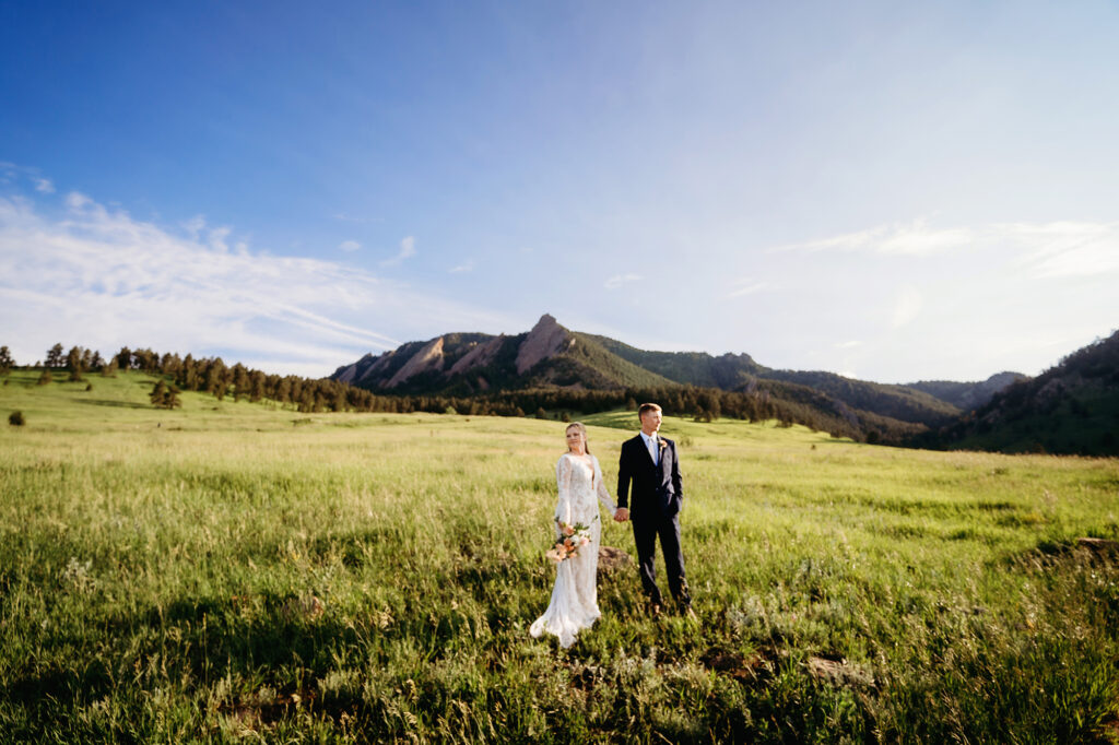 Colorado elopement photographer captures bride and groom standing in field holding hands