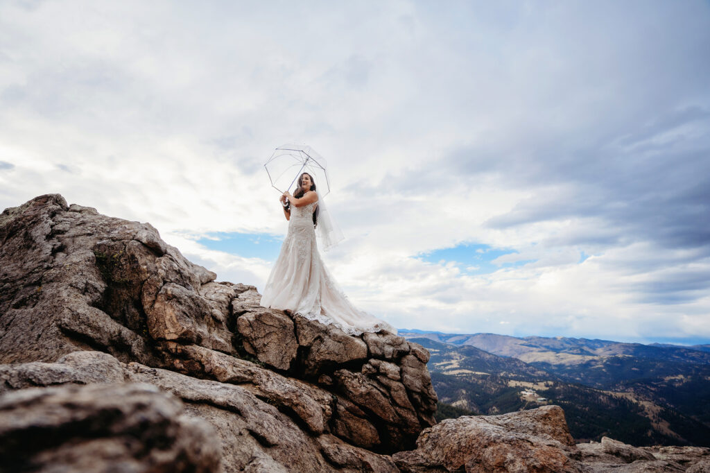 Colorado elopement photographer captures bride standing on mountain holding umbrella