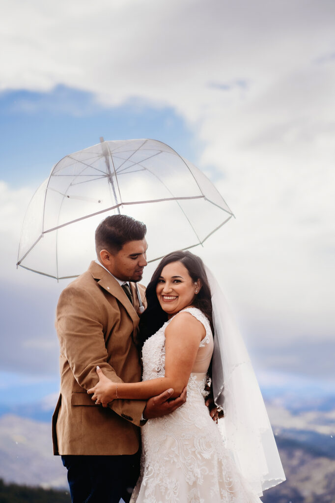 Colorado elopement photographer captures bride and groom portraits with clear umbrella after micro wedding