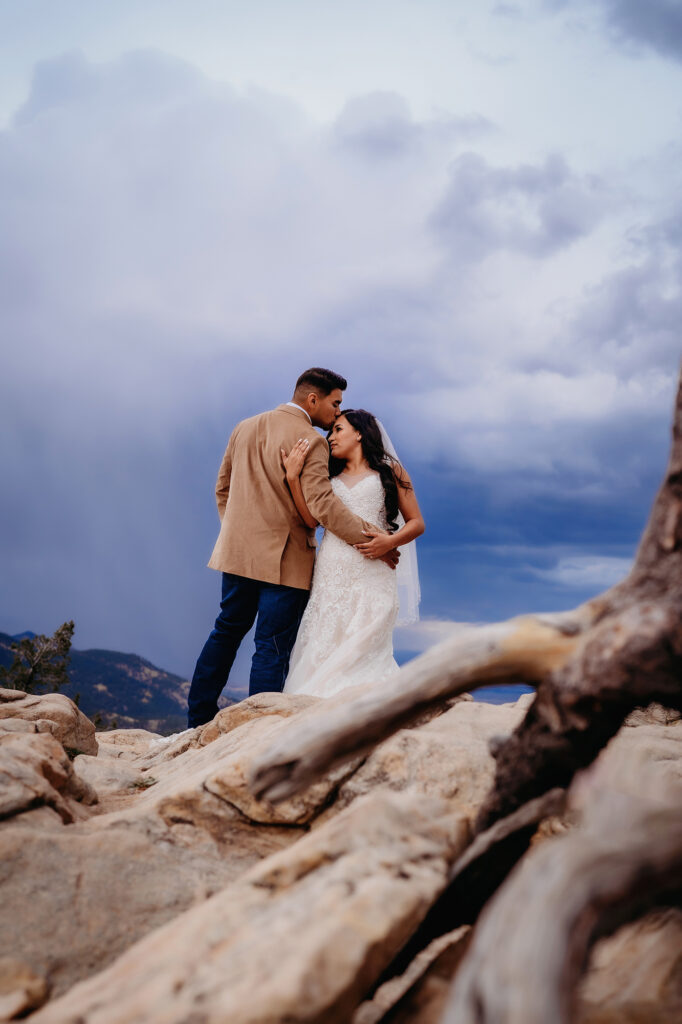 Colorado elopement photographer captures bride and groom hugging on top of mountain after micro wedding