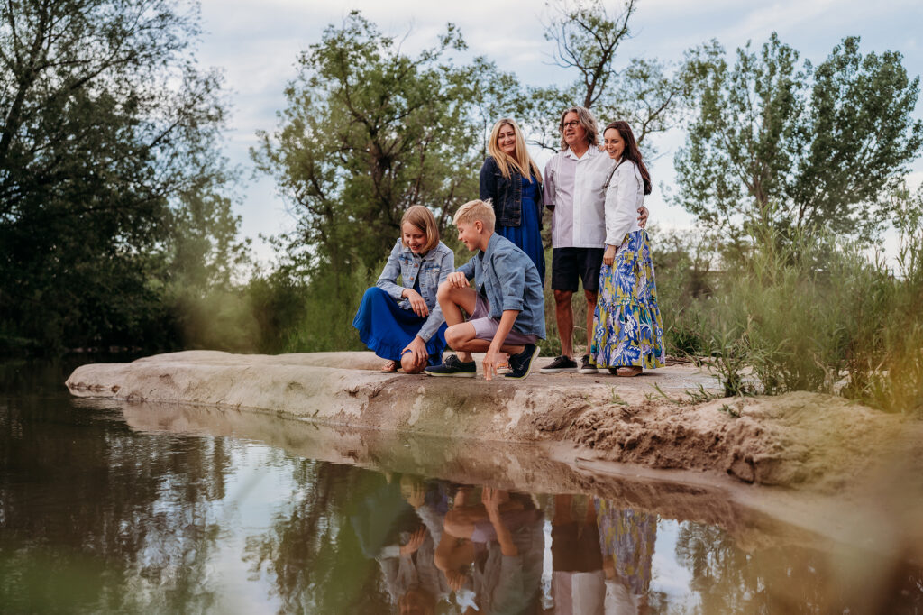 Denver Family Photographers capture family standing alongside water before outdoor family photo session