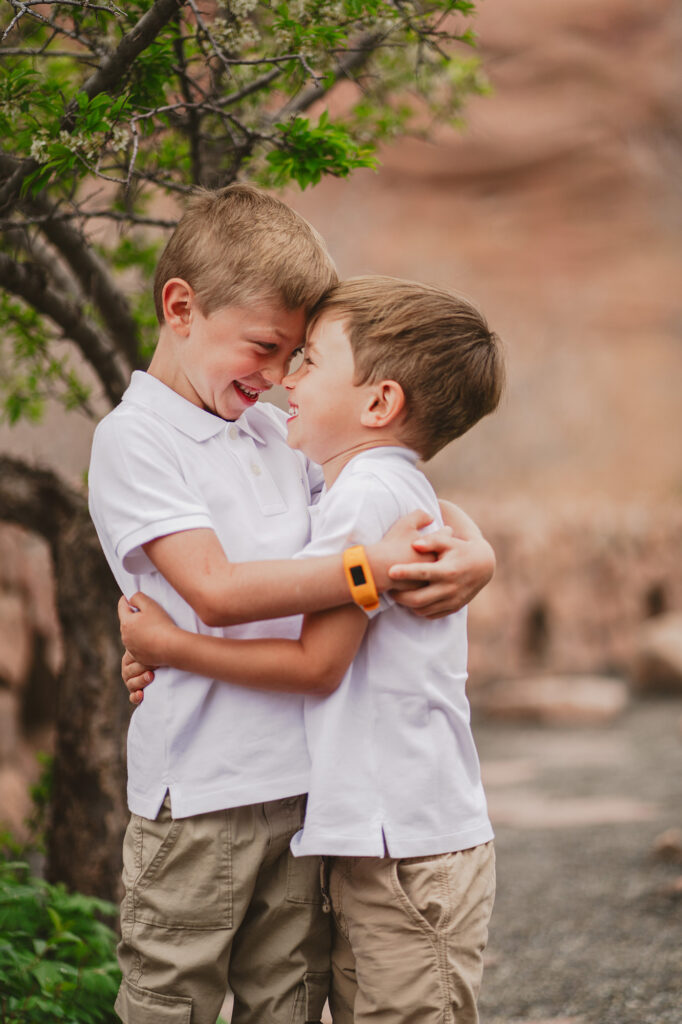 two young brother with their arms wrapped around each other and and resting their foreheads together as they smile captured by Denver family photographers