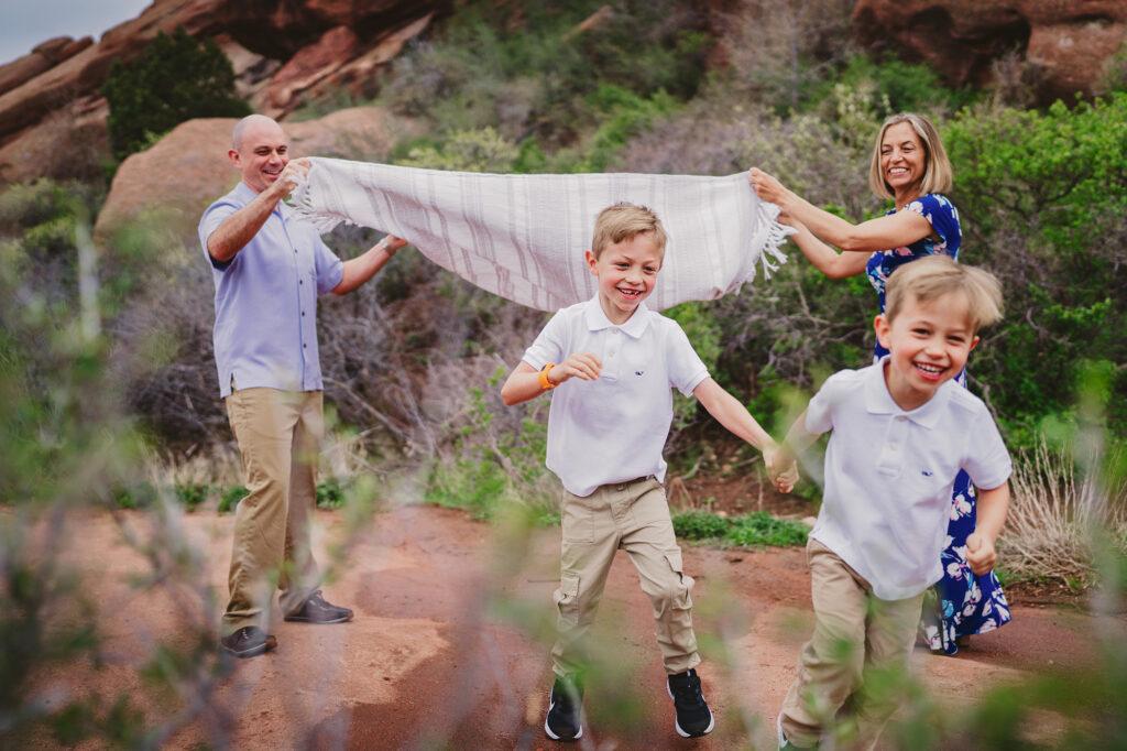 two little boys running under a blanket that their parents are waving in the air for their colorado family pictuers