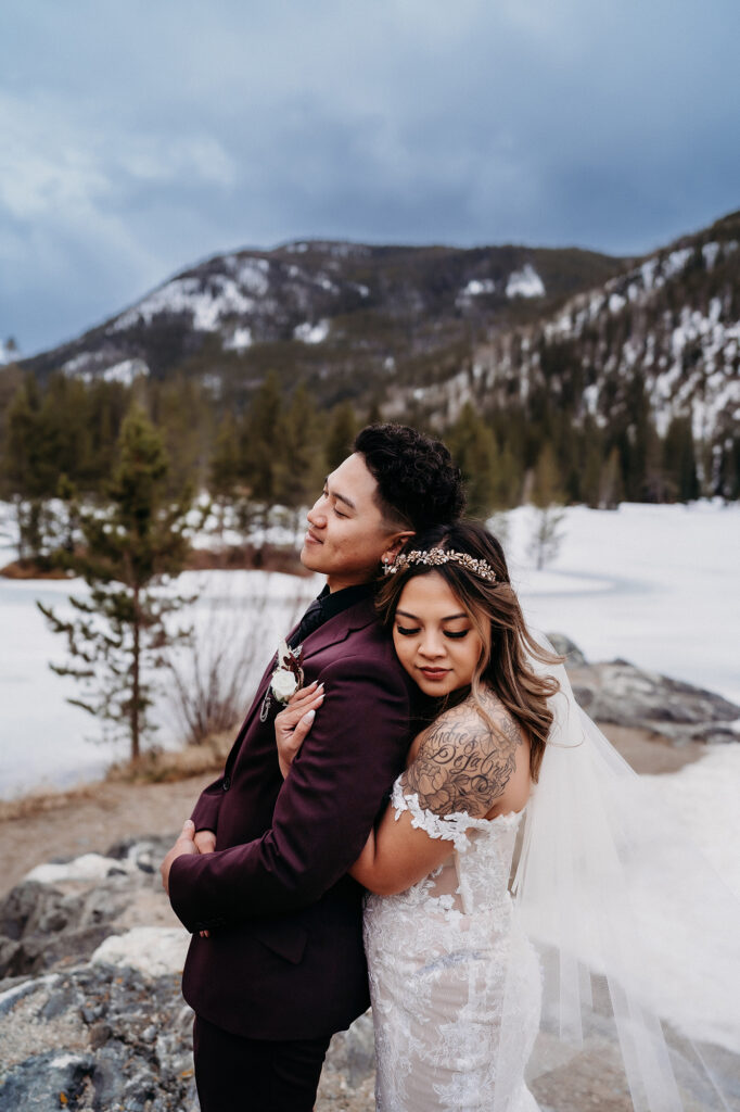 Colorado elopement photographer captures bride hugging groom from behind during outdoor bridal portraits