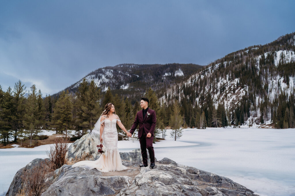 Colorado elopement photographer captures bride and groom holding hands on boulder during destination Colorado elopement