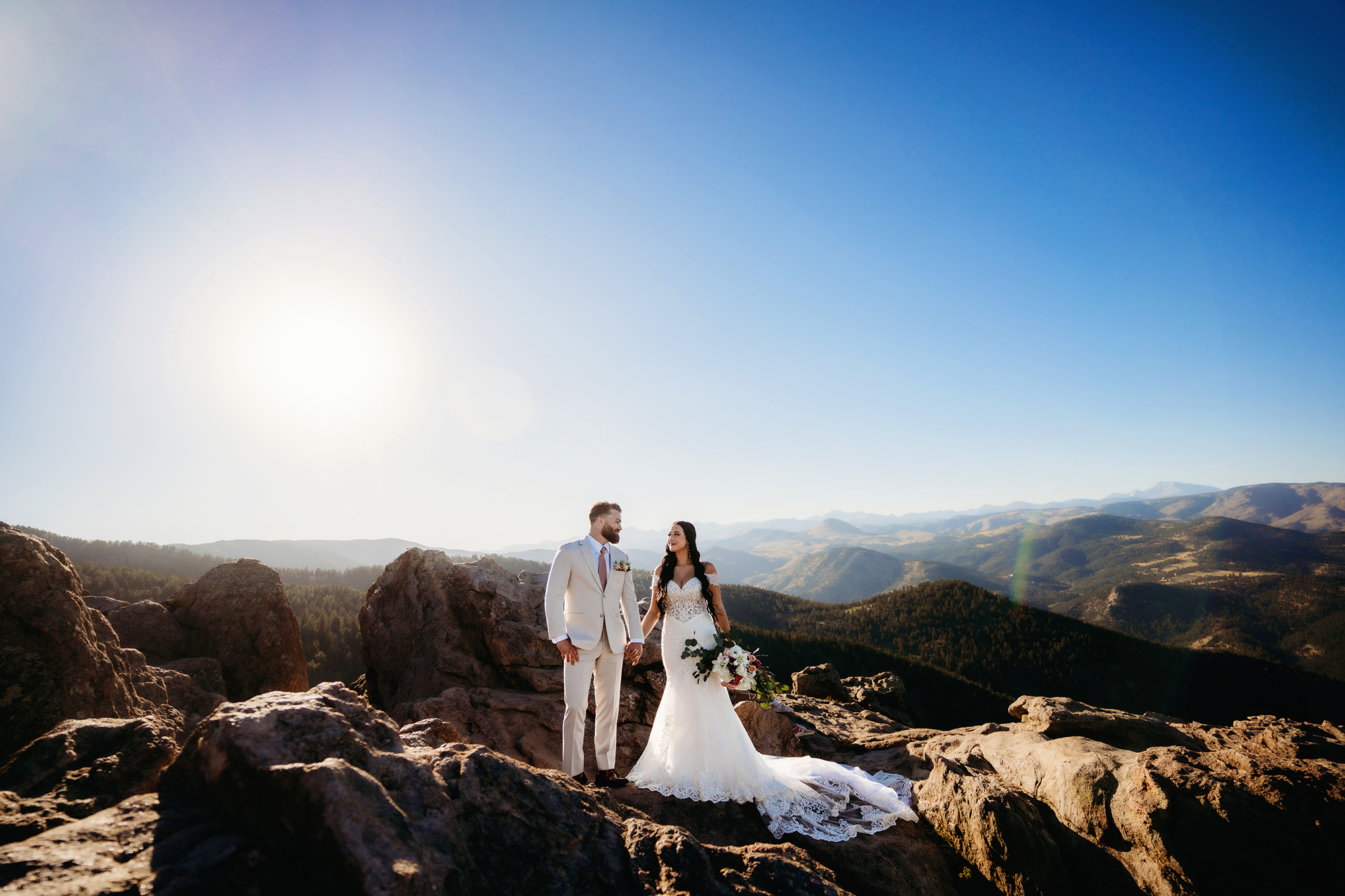 Colorado elopement photographer captures bride and groom standing hand in hand on boulder