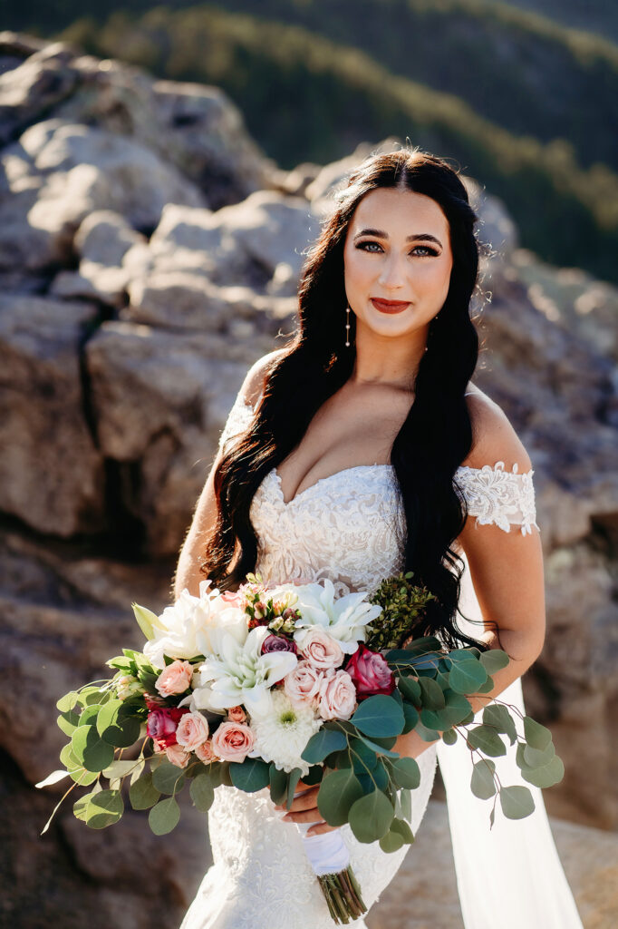 Colorado elopement photographer captures bride holding bridal bouquet while standing in front of rocks after wedding day hike