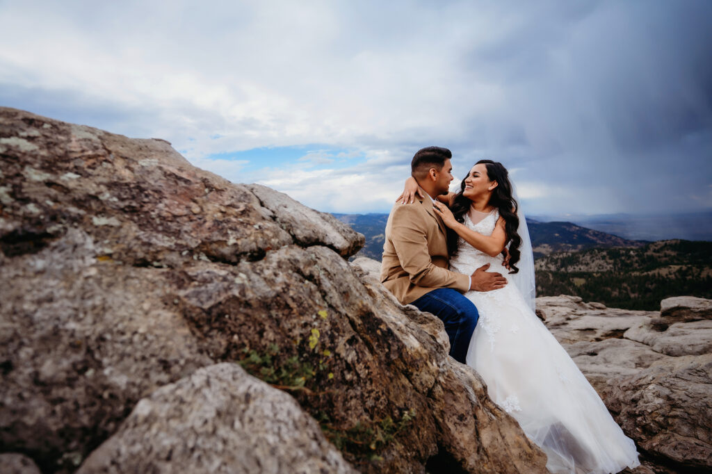 Colorado elopement photographer captures couple leaning against boulder smiling 