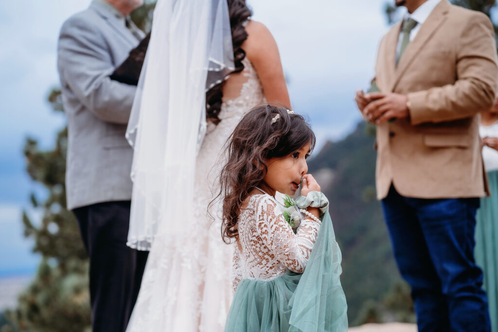 Colorado elopement photographer captures little girl wearing white and green dress at alter next to mother and father