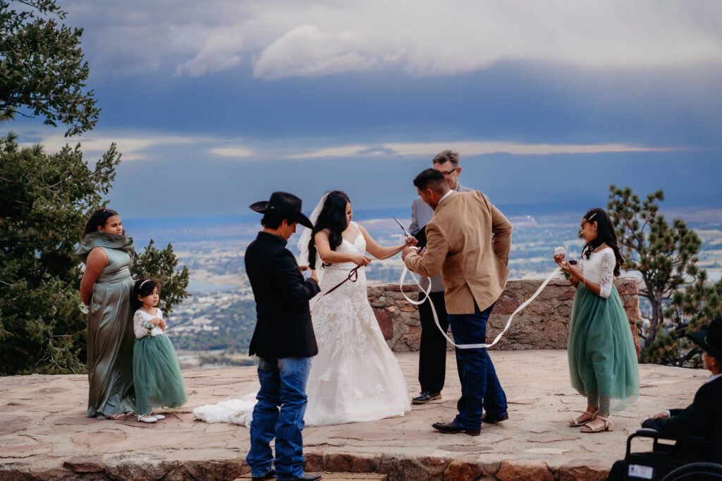 Colorado elopement photographer captures husband and wife performing ribbon-tying ceremony with children for unique ways to include children in elopement ceremony
