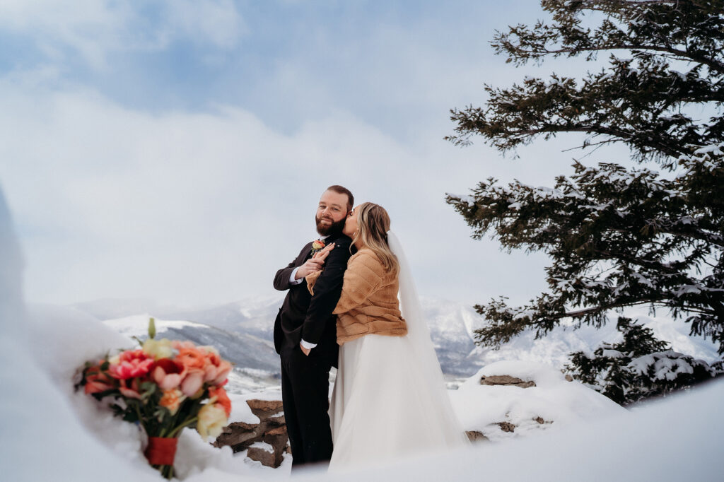 Bride and groom embrace on mountaintop 