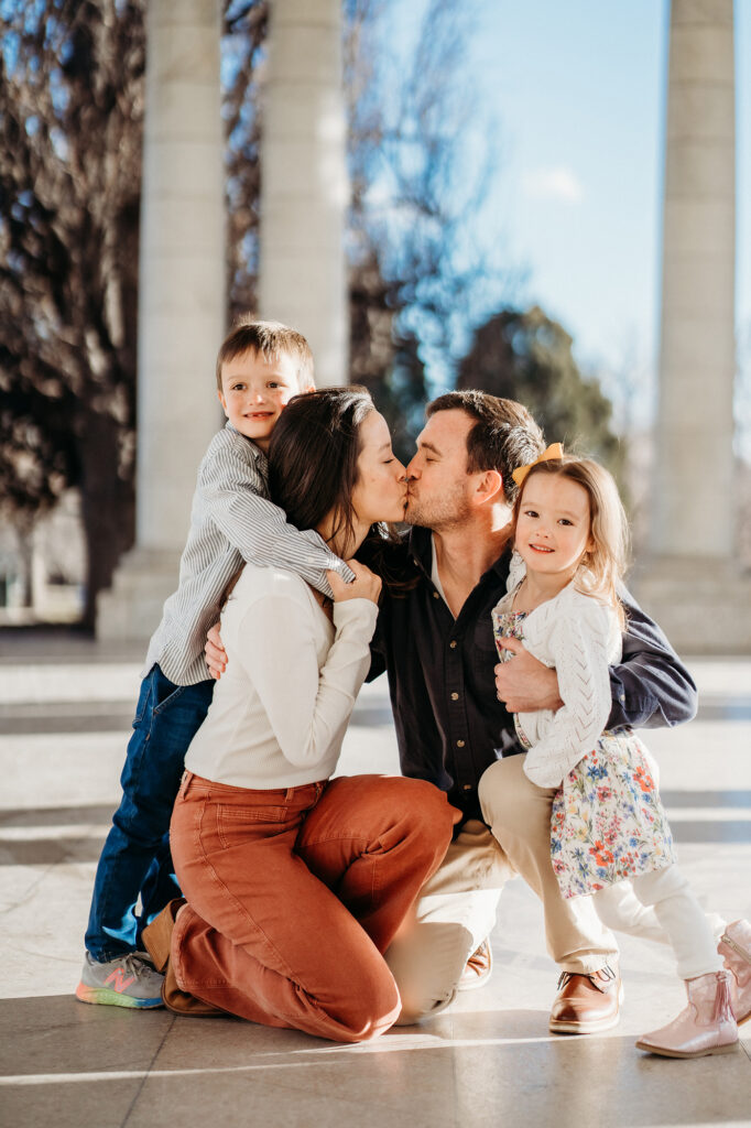 Denver Family Photographers capture mother and father kissing while children smile