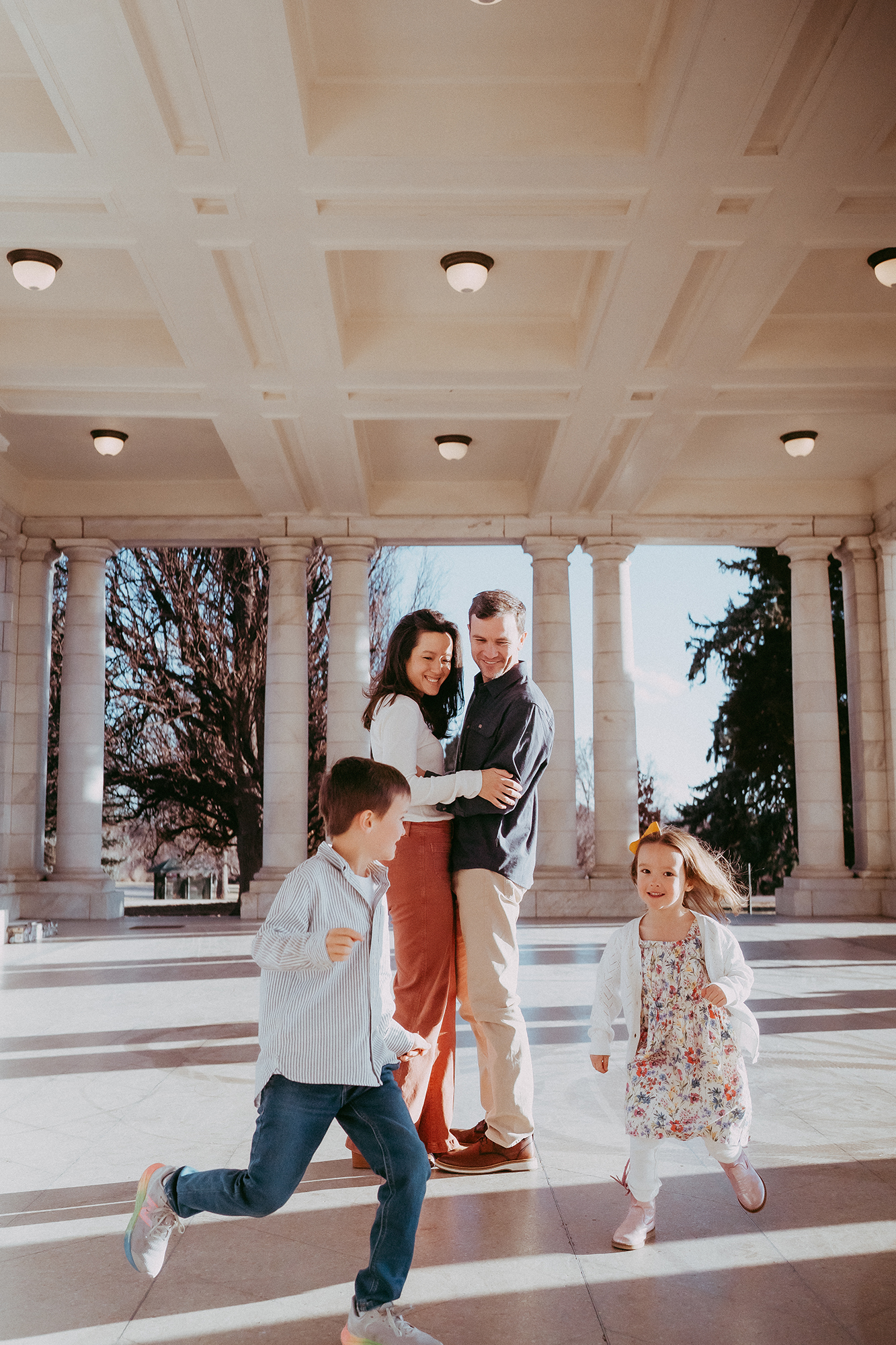 Colorado Family Photographer captures mother and father hugging while children run around them