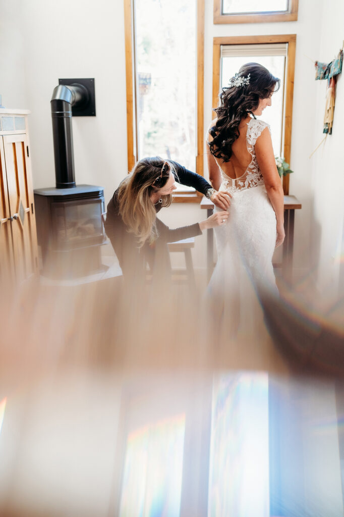 Colorado Elopement Photographer captures bride getting buttoned up into dress