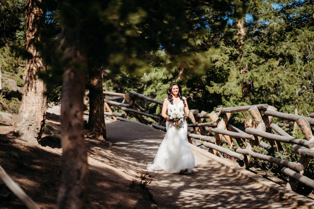 Colorado Elopement Photographer captures bride walking across bridge with bouquet