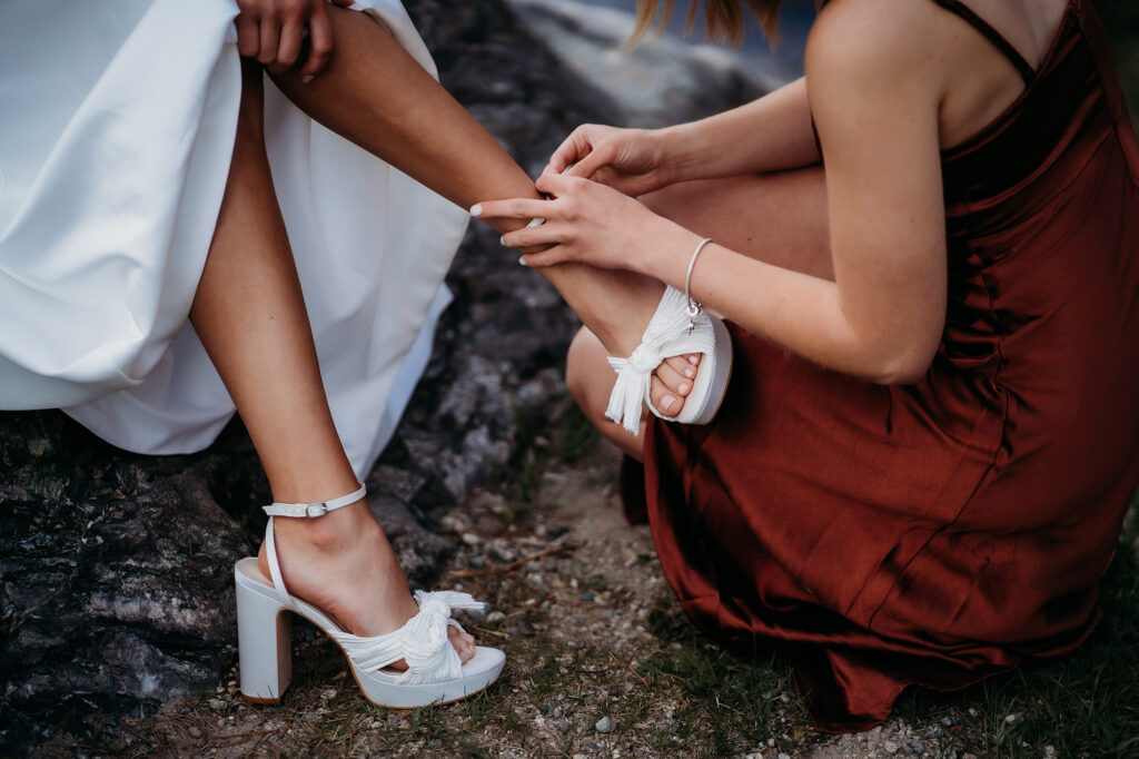 Colorado Elopement Photographer captures bridesmaid helping bride put on shoes