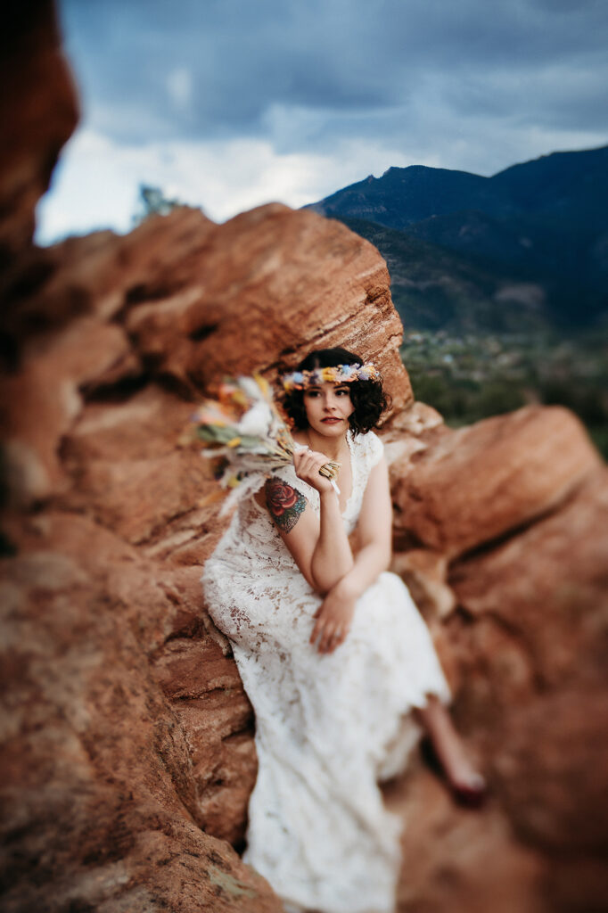 Denver Wedding Photographer captures bride sitting on rock holding bouquet