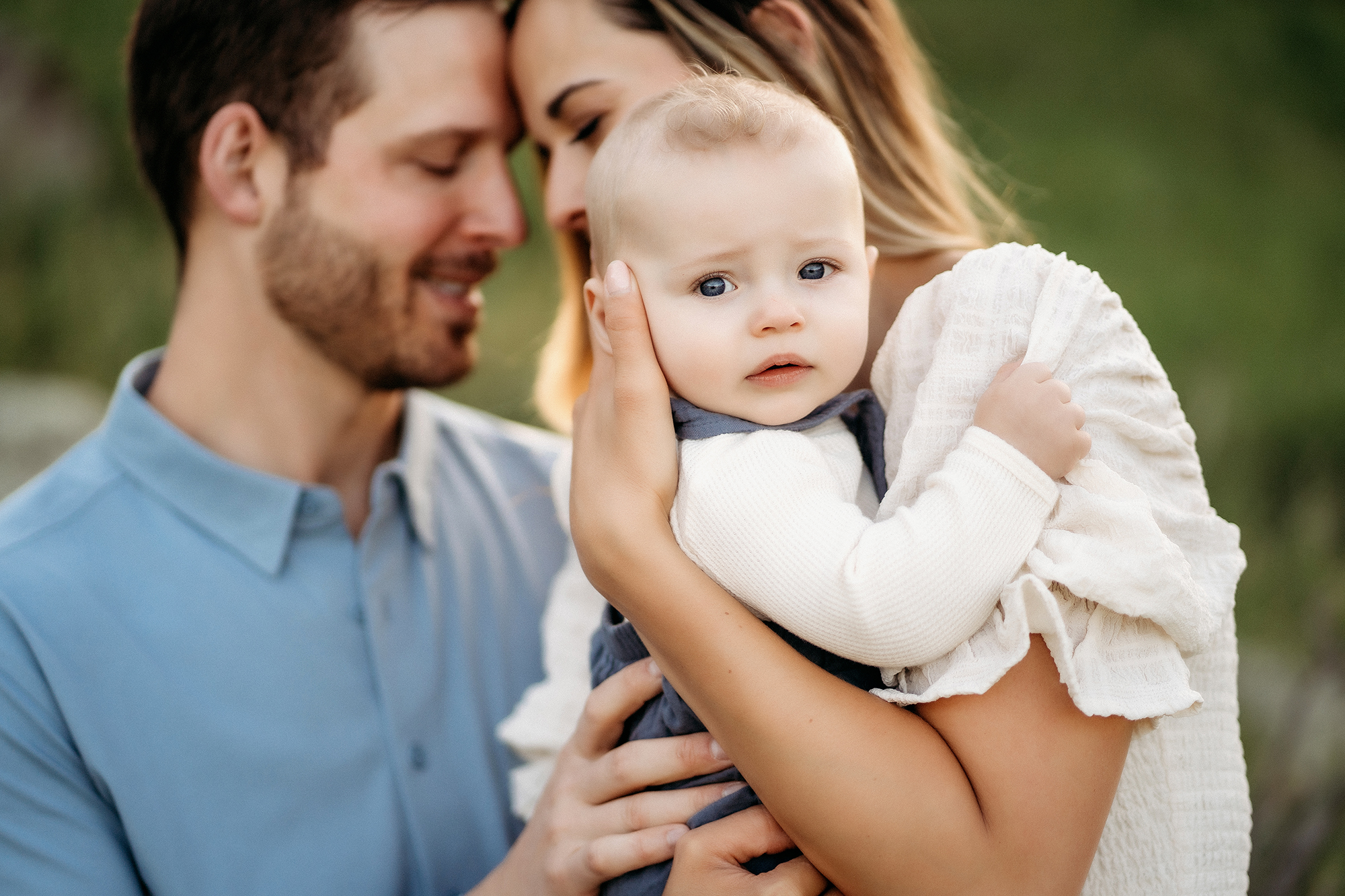 Denver Family Photographers capture parents touching foreheads while holding baby