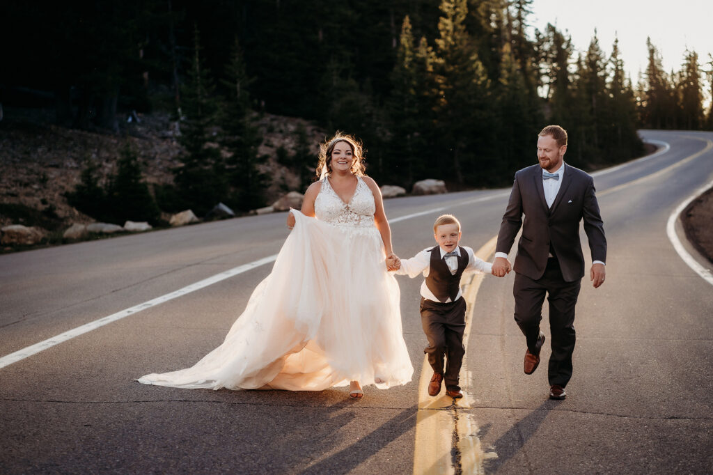 Colorado elopement photographer captures bride and groom running through street with son after elopement