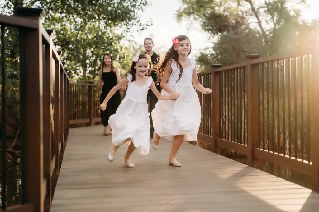 Denver Family Photographer captures sisters running across bridge during family photos