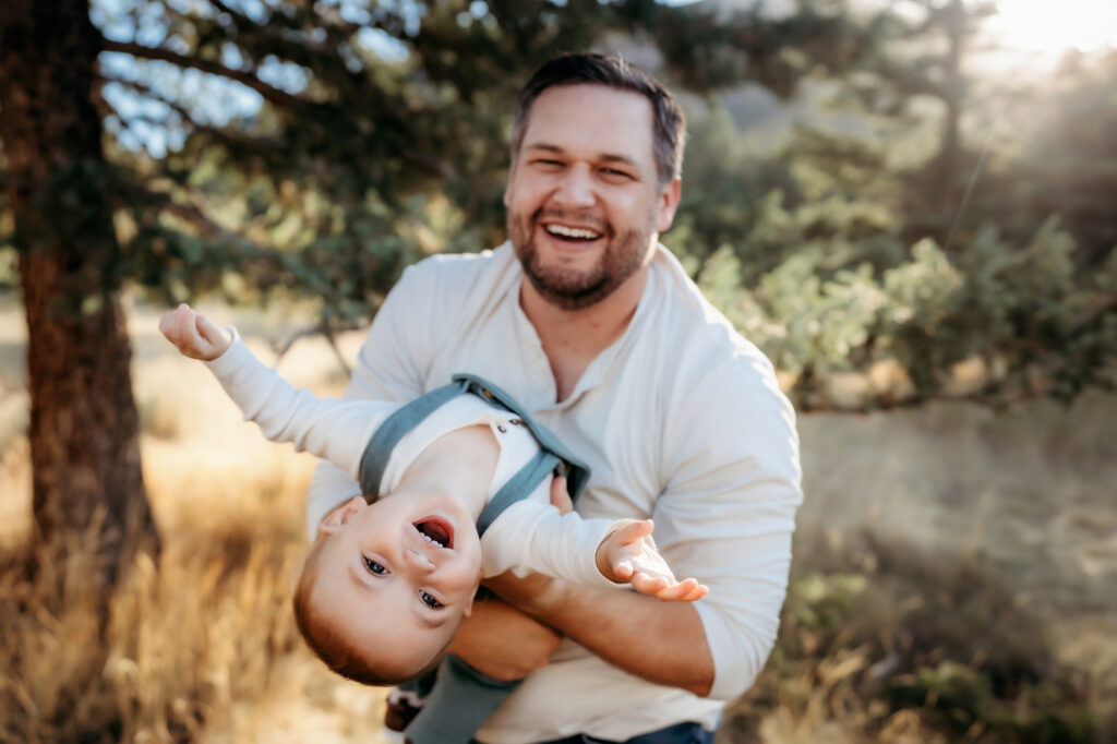 Denver Family Photographer captures father holding baby and lifting him upside down